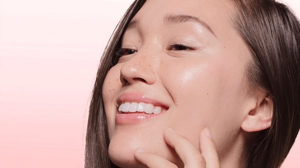 Smiling woman touching her glowing skin